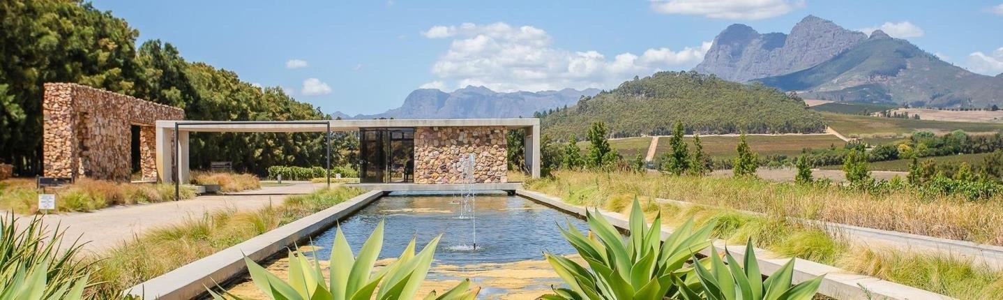 A stone pavilion and reflecting pool with the mountains behind